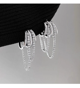Macro detail of silver tassel earrings with multi-layer chains and zircon stones