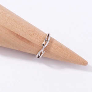 Detail view of silver wave-shaped ring with zircon stones on wooden display cone
