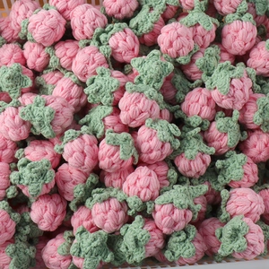 Detailed view of handmade pink crocheted strawberries with green leaves and soft texture