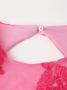 Détail de l'encolure dos rose avec broderie florale délicate et fermeture à bouton blanc