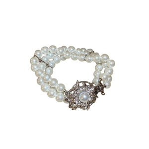 Elegant multi-layer pearl bracelet with a sparkling diamond flower clasp on white background