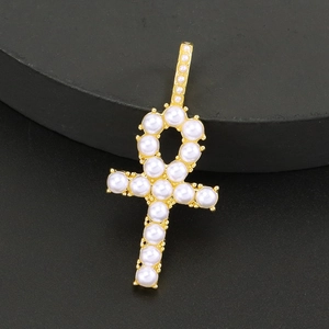Detailed shot of gold Ankh cross pendant featuring white pearls on black background