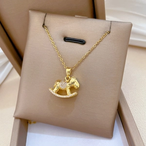 Detail shot of a golden rocking horse necklace with zircon stones in a jewelry box