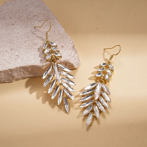 Elegant gold-tone leaf earrings featuring teardrop crystals on a neutral stone backdrop