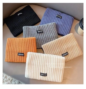 Detail showing various colors of knitted rib scarves with GRANK brand labels