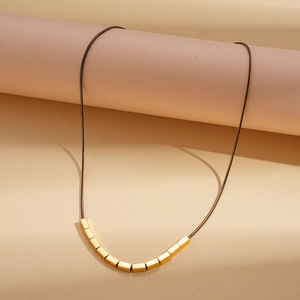 Detailed macro shot of 18k gold-plated cube beads on a minimalist black necklace cord