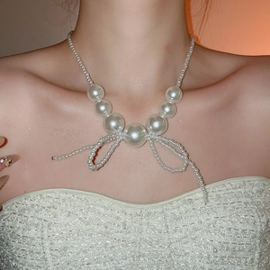 Elegant pearl necklace featuring a bow design worn by a model in a close-up detail shot