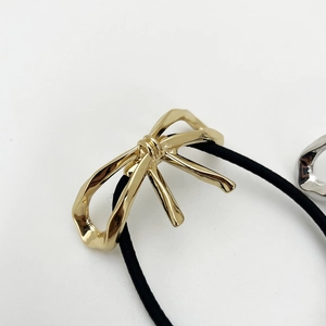 Eleganter goldener Schleifenhaargummi mit schwarzem Gummiband auf weißem Grund