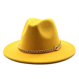 Macro detail of yellow wool fedora hat featuring a bold gold metal chain decoration