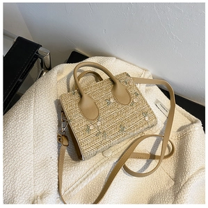 Close-up of straw woven bag with exquisite white floral embroidery and thin leather strap