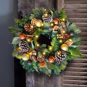 Illuminated Christmas wreath with pine cones and cinnamon sticks on a wooden background