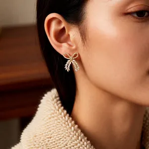 Elegant gold-plated bow earrings with white cubic zirconia worn by a model