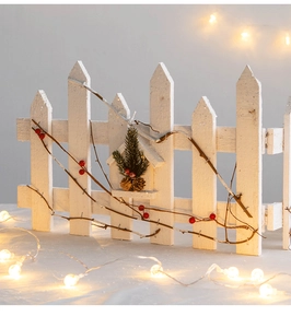 White wooden picket fence decoration with birdhouse and red berries for Christmas tree