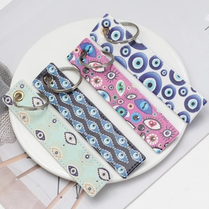 Close-up of artificial leather evil eye keychains in four colors on a white plate