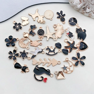 Flat lay of diverse gold and black enamel charms including hearts cats and moons