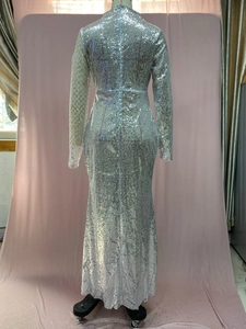 Detail of silver sequin evening gown featuring high neck, long sleeves, and mermaid hemline