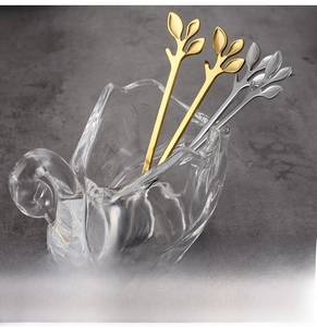 Macro detail of leaf-shaped stainless steel dessert spoons in gold and silver finish