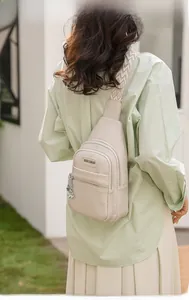 Dettaglio della borsa a tracolla beige in pelle martellata con ciondolo a quadrifoglio