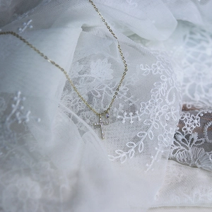 Detailed view of S925 silver cross pendant with clear zircons on delicate gold chain