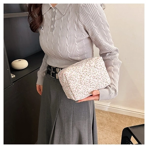 Detail of floral cotton makeup bag held by a model showcasing its large capacity and soft texture
