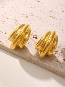 Detailed view of gold croissant earrings with spiral texture on a beige stone base