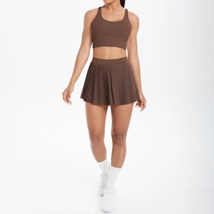 Détail d'un ensemble brassière de sport marron et jupe plissée en tissu extensible