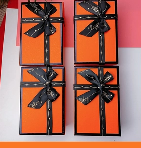 Detailed top view of orange gift boxes with black Happy ribbons and elegant bow ties