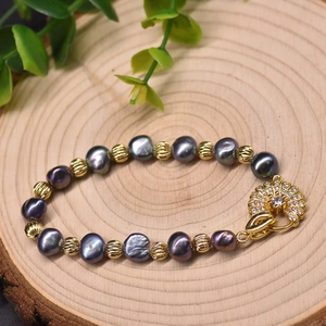 Bracelet en perles violettes avec billes dorées et fermoir en zircon sur socle en bois
