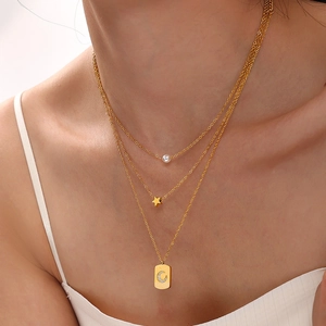 Gold multi-layer necklace with pearl, star pendant and moon rectangle tag on a model