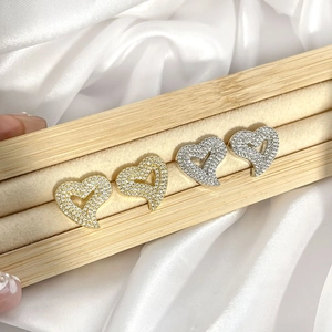 Macro detail of heart-shaped earrings in gold and silver with zircon pavé setting