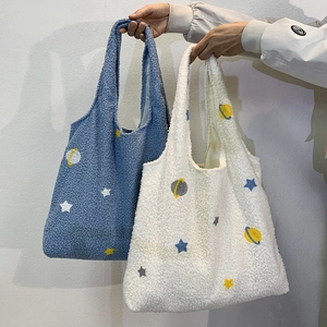 Close-up detail of soft lamb wool tote bag with embroidered star and planet patterns