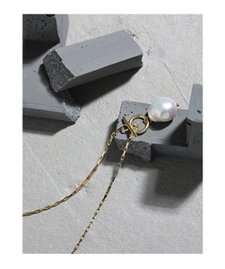 Detailed shot of baroque pearl pendant on golden chain with OT clasp over grey stone