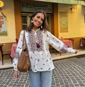 Detail der Bohème-Bluse in Creme mit burgunderroter Stickerei und Quasten-V-Ausschnitt