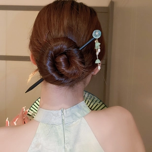 Detail view of a black wooden hair pin with light blue flowers and pearl tassels