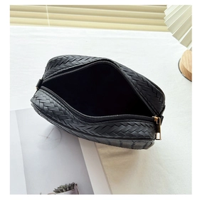 Detail of black woven leather bag featuring a gold zipper and minimalist interior lining