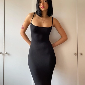 Close-up of sleek black sleeveless bodycon maxi dress in elastic knit fabric