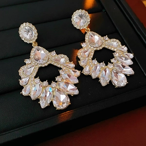 Gros plan détaillé de grandes boucles d'oreilles dorées avec cristaux transparents