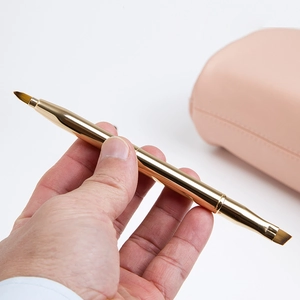 Detailansicht der ausziehbaren Lippen- und Concealer-Doppelbürste aus goldenem Metall