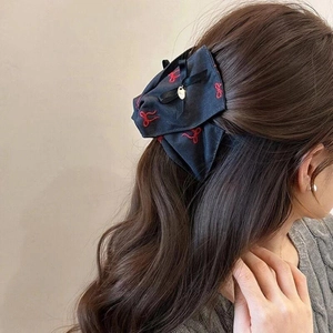 Elegant navy bow hair claw with red embroidery and gold charm on brown hair
