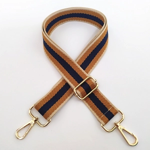Detail of thickened canvas bag strap with brown navy stripes and golden metal clasps