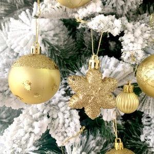 Dettaglio di addobbi natalizi dorati con fiocchi glitterati su un albero innevato