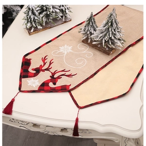 Close-up of linen Christmas table runner with red reindeer and snowflake prints