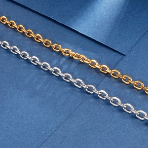 Macro shot of gold and silver stainless steel O-link chains on a dark textured surface