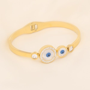 Golden Evil Eye open bangle featuring crystal rhinestones on a beige silk background