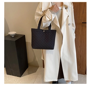 Dettaglio borsa shopper trapuntata nera con bottone d'argento e trench elegante