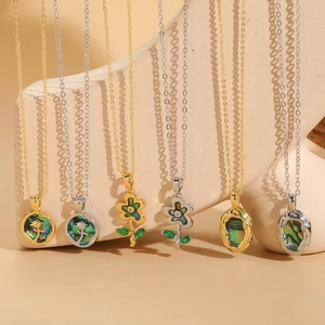 Exquisite abalone shell flower necklaces with green stones on a neutral display stand