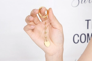 Detailed close-up of golden heart-shaped long chain keychain held by a model