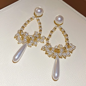 Close-up of gold drop fringe pearl earrings with elegant beaded texture on beige leather