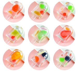 Close-up of transparent resin popsicle charms with realistic embedded fruit slices