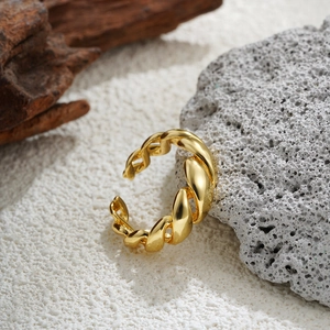Detailed view of an 18K gold-plated twisted chain ring placed on a decorative white stone